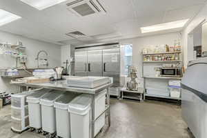Kitchen featuring appliances with stainless steel finishes, concrete floors, and a drop ceiling