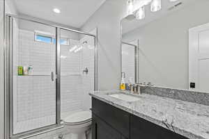 Bathroom with walk in shower, toilet, and large vanity