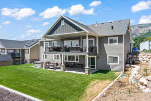 Back of property featuring solar panels, outdoor lounge area, a patio, a balcony, and a lawn