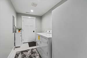 Clothes washing area with light tile floors and washing machine and clothes dryer