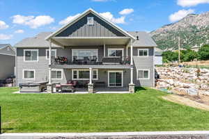 Rear view of house with a patio area, an outdoor hangout area, a mountain view, a balcony, and a yard