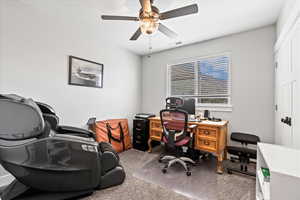 Carpeted home office featuring ceiling fan