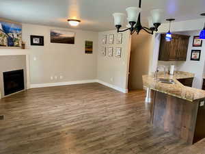 Kitchen with sink, dark hardwood / wood-style flooring, decorative light fixtures, dark brown cabinetry, and a chandelier