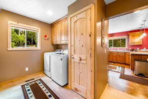 Laundry area with plenty of natural light, washing machine and dryer, a textured ceiling, and cabinets