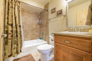 Full bathroom with vanity, toilet, tile patterned floors, and shower / bathtub combination with curtain