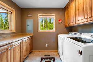 Laundry room with separate washer and dryer, cabinets, electric panel, and light tile patterned floors