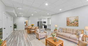 Living room with light hardwood / wood-style flooring and a paneled ceiling