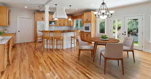 Dining space with french doors, light wood-type flooring, a chandelier, and a wealth of natural light