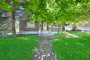 View of property hidden behind natural elements with a front yard