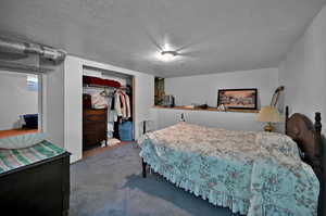 Carpeted bedroom featuring a textured ceiling and a closet