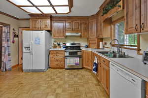 Kitchen featuring ornamental molding, light parquet floors, sink, and white appliances