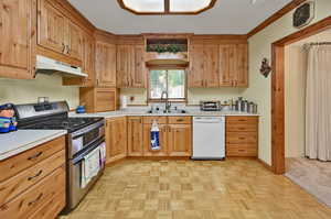 Kitchen featuring sink, range with two ovens, white dishwasher, and light colored carpet