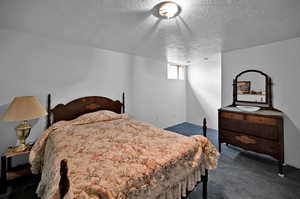 Bedroom with dark colored carpet and a textured ceiling