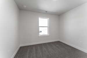 Unfurnished room with a textured ceiling and dark carpet