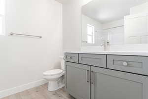 Bathroom with walk in shower, wood-type flooring, toilet, and vanity