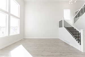 Interior space with a towering ceiling, light hardwood / wood-style flooring, and an inviting chandelier