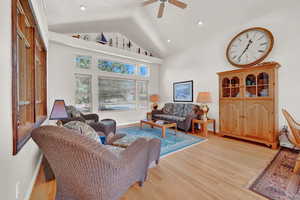 Living room featuring high vaulted ceiling, ceiling fan, and light hardwood / wood-style floors