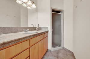 Bathroom featuring walk in shower, vanity, and tile floors