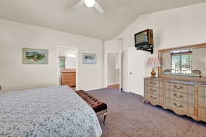 Primary Bedroom. Carpeted bedroom with ceiling fan, vaulted ceiling, and connected bathroom