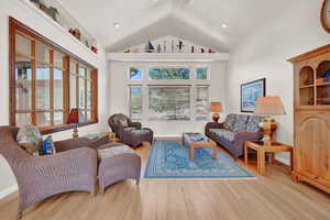 Living room with high vaulted ceiling and light hardwood / wood-style flooring