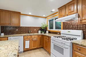 Kitchen featuring sink, crown molding, white appliances, and backsplash