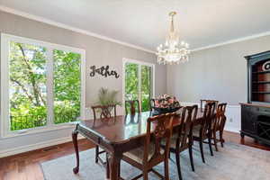 Dining area with hardwood / wood-style flooring, a chandelier, and ornamental molding