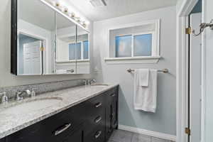 Bathroom featuring double vanity, tile patterned flooring, and a textured ceiling