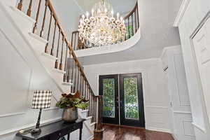 Foyer entrance with a notable chandelier, french doors, a textured ceiling, dark wood-type flooring, and ornamental molding