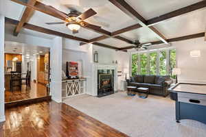 Living room with a premium fireplace, carpet, ceiling fan, and coffered ceiling