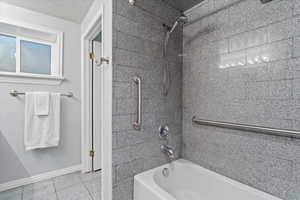 Bathroom with a textured ceiling, tiled shower / bath, and tile patterned flooring