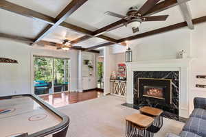 Interior space with a premium fireplace, beamed ceiling, hardwood / wood-style floors, ceiling fan, and coffered ceiling