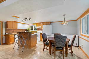 Kitchen featuring backsplash, white appliances, a kitchen island, and a textured ceiling