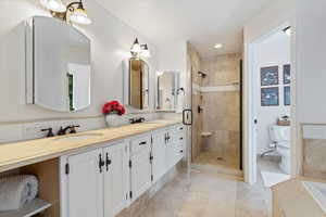 Bathroom featuring tiled shower, backsplash, toilet, dual vanity, and tile patterned floors