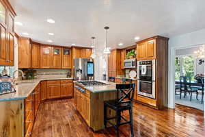 Kitchen with a chandelier, stainless steel appliances, dark hardwood / wood-style flooring, sink, and a kitchen island