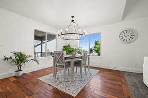 Dining area with a notable chandelier, dark hardwood / wood-style flooring, and a wealth of natural light