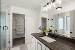 Bathroom with a shower with shower door, vanity, and tile patterned flooring