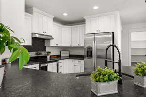 Kitchen with appliances with stainless steel finishes, white cabinetry, and tasteful backsplash