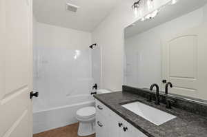 Full bathroom with tile patterned floors, toilet, vanity, and shower / bathtub combination