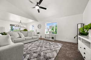 Living room featuring dark colored carpet, ceiling fan with notable chandelier, and lofted ceiling