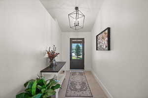 Doorway to outside with tile patterned flooring and an inviting chandelier