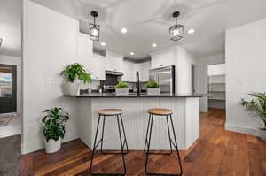 Kitchen featuring dark hardwood / wood-style floors, kitchen peninsula, stainless steel appliances, and white cabinets