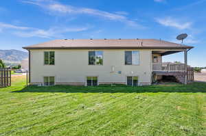 Back of property featuring a yard and a wooden deck