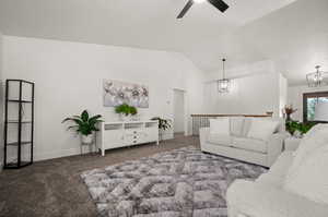 Carpeted living room featuring ceiling fan with notable chandelier and vaulted ceiling