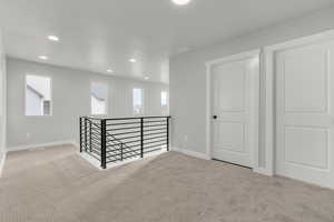 Basement featuring light colored carpet, a healthy amount of sunlight, and a textured ceiling