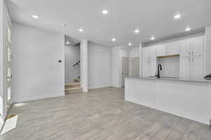 Kitchen with sink, light wood-type flooring, and white cabinets