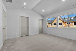 Unfurnished bedroom with lofted ceiling and light colored carpet