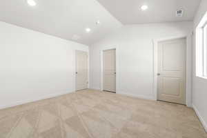 Unfurnished bedroom with lofted ceiling and light colored carpet