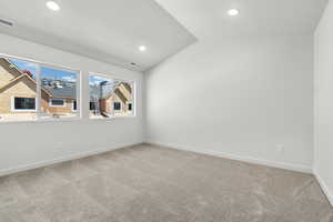 Carpeted spare room featuring lofted ceiling