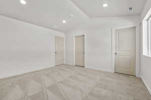 Unfurnished bedroom featuring light carpet and lofted ceiling