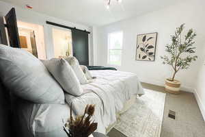 Carpeted bedroom with connected bathroom and a barn door